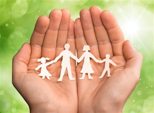 two hands holding a paper cut out of a family